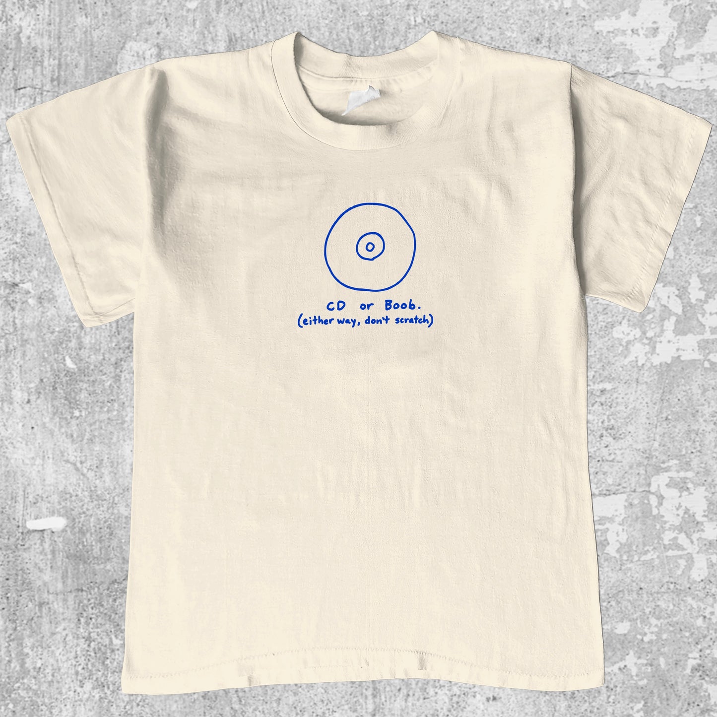 CD or Boob graphic tee with bold and humorous print, funny and trendy graphic. Perfect for adults and gift-giving. Cream shirt.