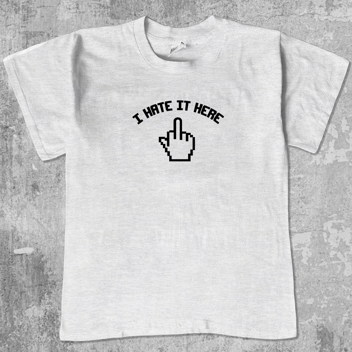I Hate It Here graphic tee with bold and humorous print, funny and trendy graphic. Perfect for adults and gift-giving. Ash Grey shirt.