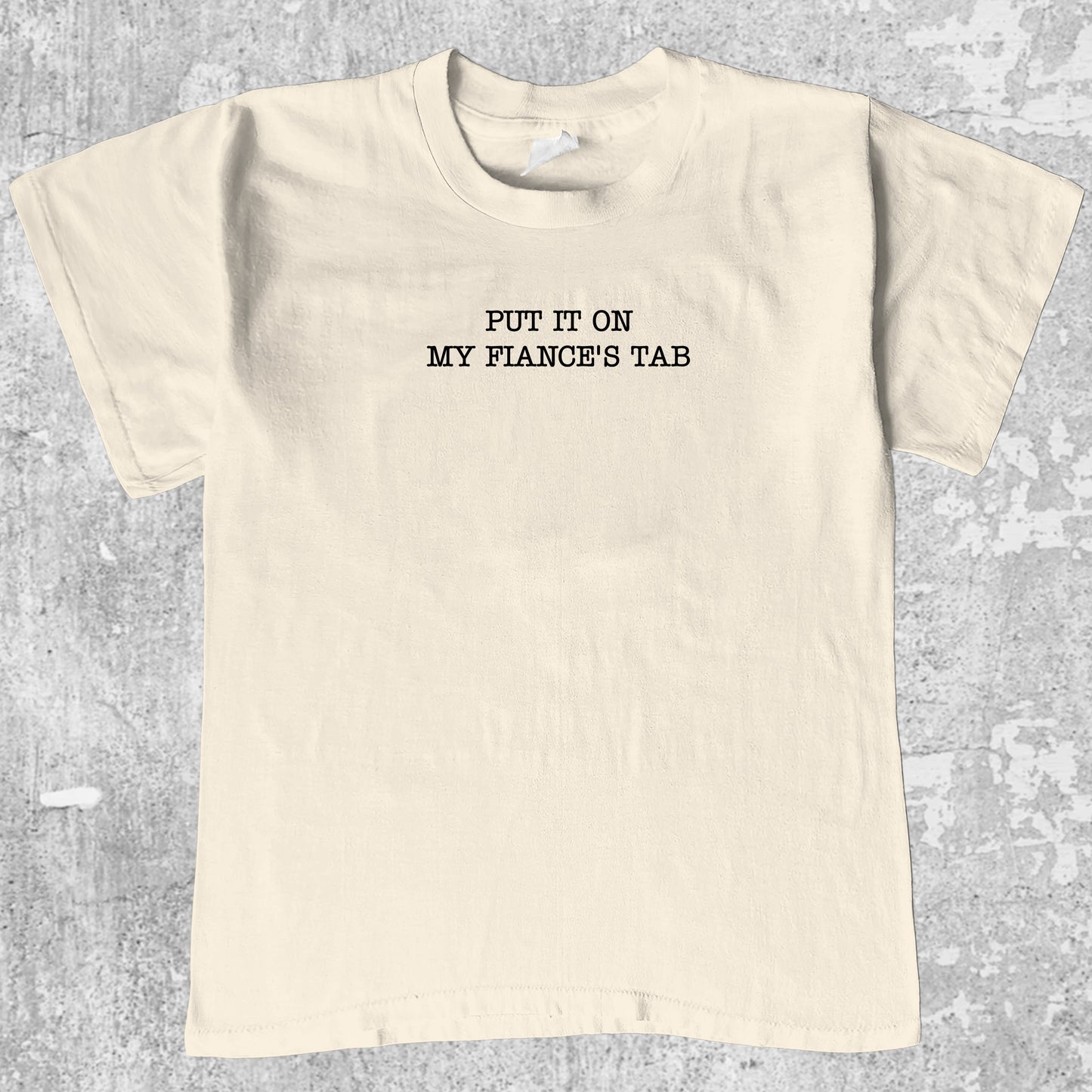 Put It On My Fiance's Tab graphic tee with retro and humorous print, funny and trendy graphic. Perfect for adults and gift-giving. Cream shirt.