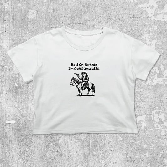 Hold On Partner I'm Overstimulated graphic crop tee with cute and trendy fit, featuring playful vintage graphic, stylish cut. White crop t-shirt