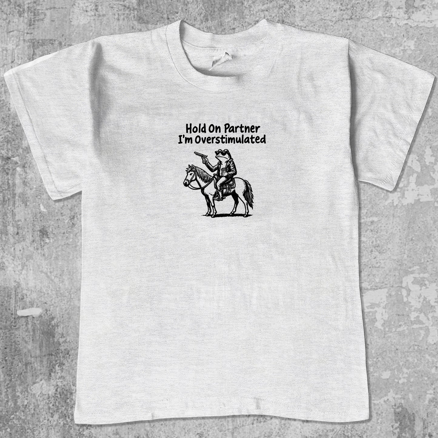 Hold On Partner I'm Overstimulated graphic tee with funny frogs print, retro and trendy graphic. Perfect for Christmas gifts for friends and family. Ash Grey shirt.