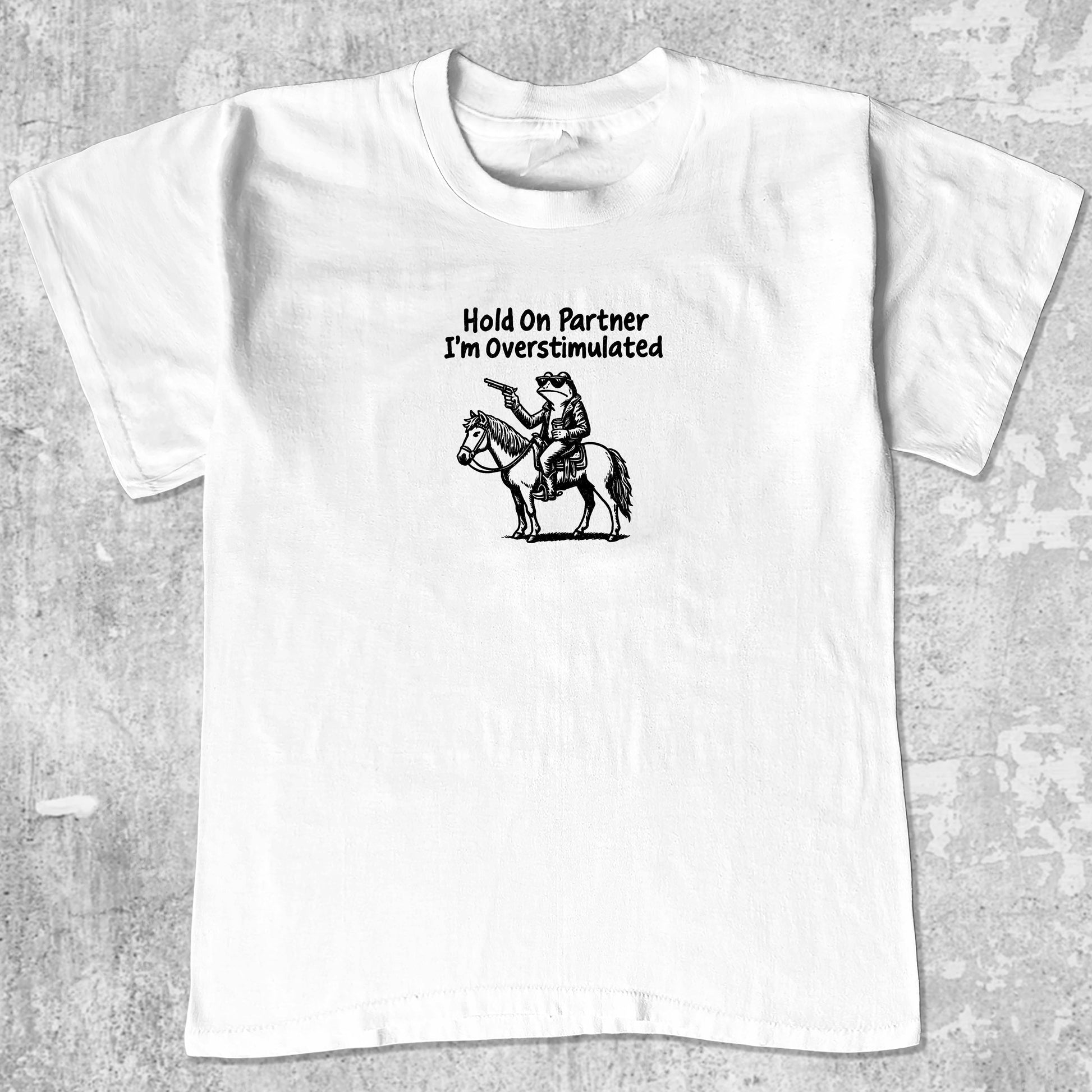 Hold On Partner I'm Overstimulated graphic tee with funny frogs print, retro and trendy graphic. Perfect for Christmas gifts for friends and family. White shirt.