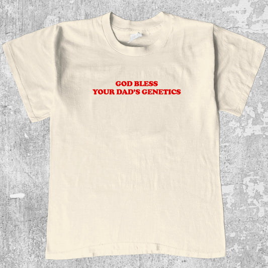 God bless your dad's genetics graphic tee with bold and humorous print, funny and trendy graphic. Perfect for adults and gift-giving. Cream shirt.