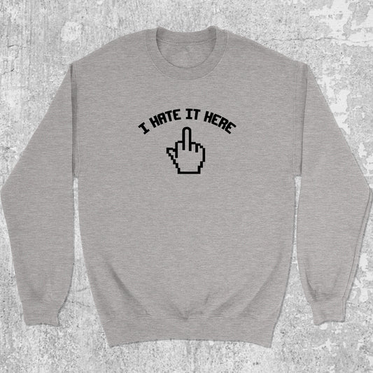 I Hate It Here graphic sweatshirt with bold and humorous print, warm and cozy graphic for everyday wear. Perfect for adults and gift-giving. Heather Grey pullover.