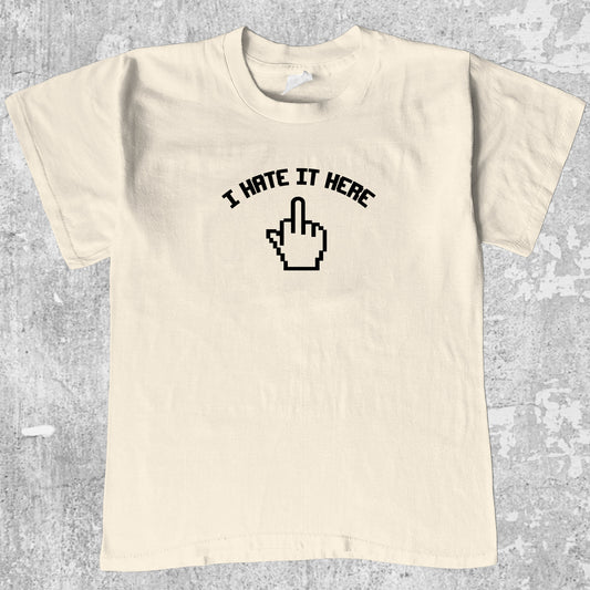 I Hate It Here graphic tee with bold and humorous print, funny and trendy graphic. Perfect for adults and gift-giving. Cream shirt.