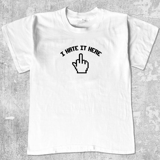 I Hate It Here graphic tee with bold and humorous print, funny and trendy graphic. Perfect for adults and gift-giving. White shirt.